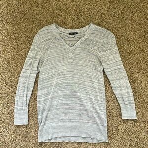 this is a grey sweater with different textures and a cross in the front.